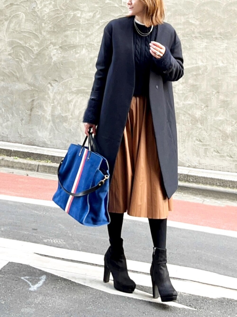 ブルー系のニット/セーター、イエロー系のスカート、ブラック系のブーツを着用したレディースの冬コーディネートの2枚目の写真