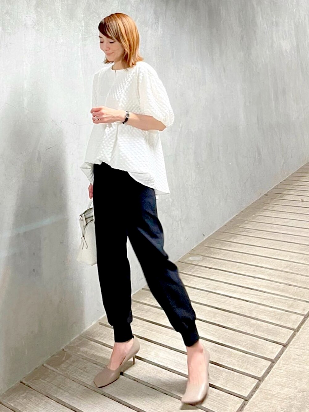 ホワイト系のハンドバッグ、グレー系のパンプス、ブラック系のその他パンツを着用したレディースの春コーディネートの3枚目の写真