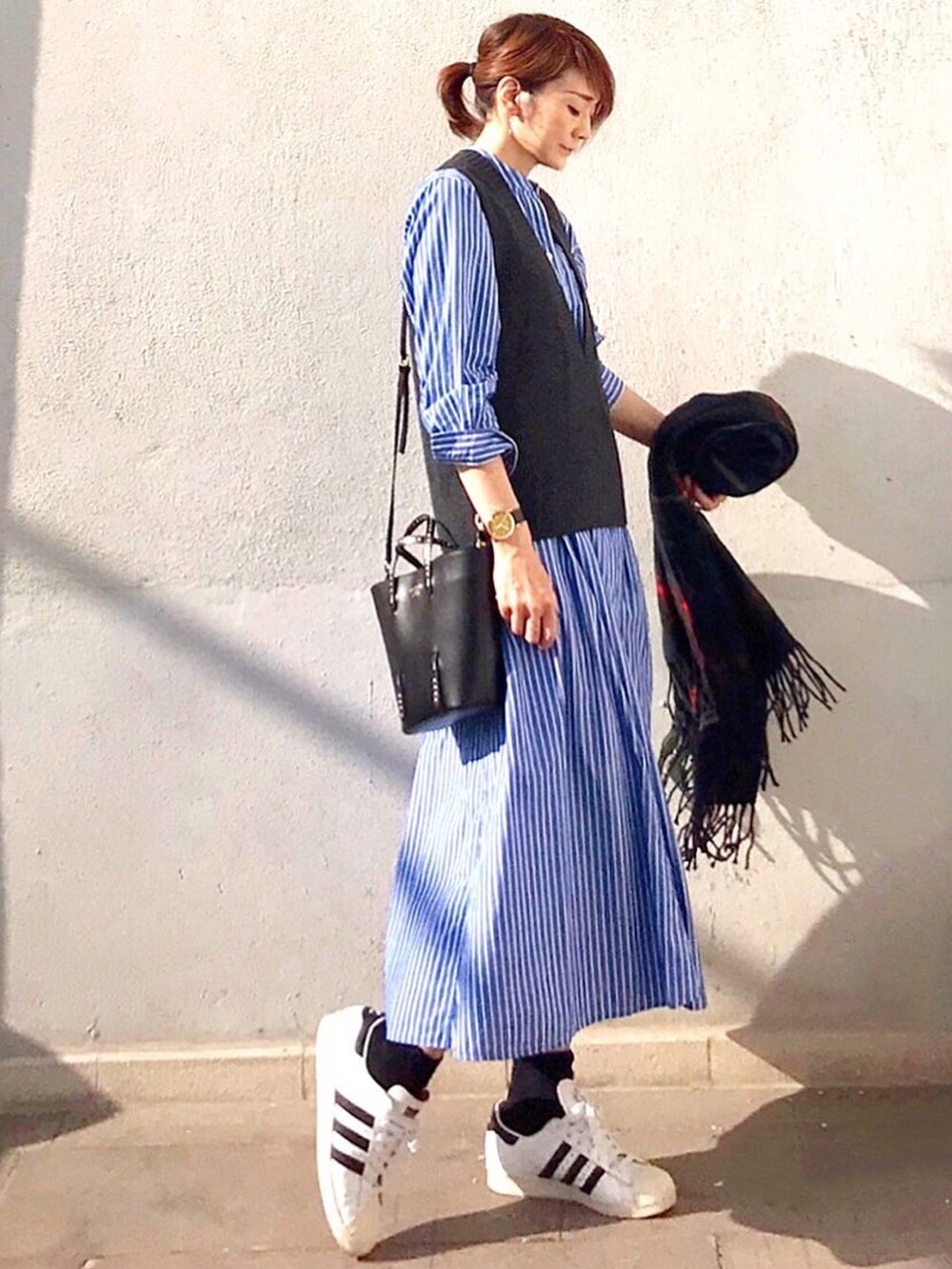 ブルー系のワンピース、グレー系のベスト、ブラック系のトートバッグを着用したレディースの秋コーディネートの2枚目の写真