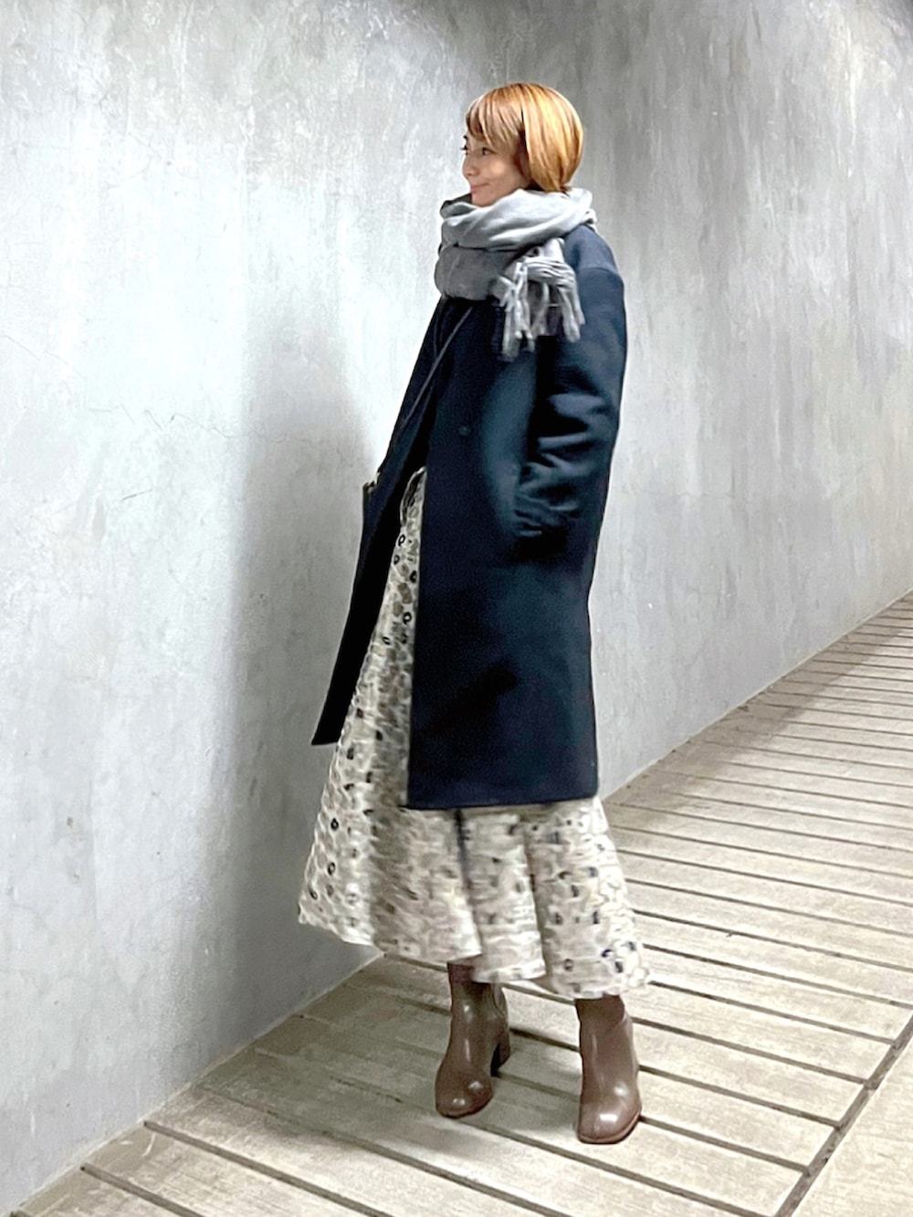 ベージュ系のスカート、ブルー系のニット/セーター、ベージュ系のブーツを着用したレディースの冬コーディネートの3枚目の写真