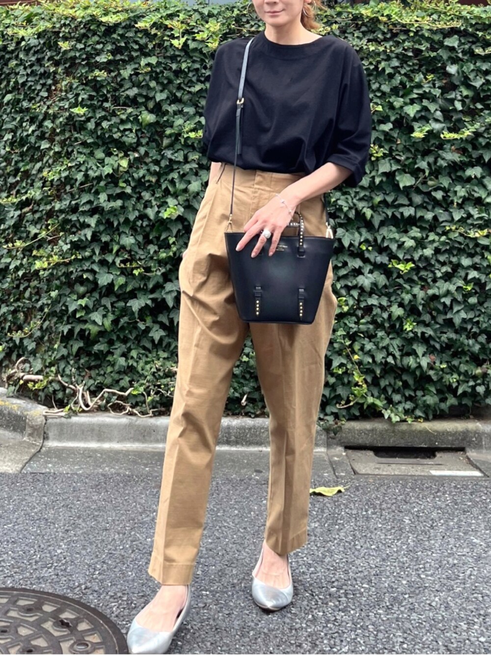 イエロー系のチノパンツ、ブラック系のトートバッグ、ブラック系のTシャツ/カットソーを着用したレディースの夏コーディネートの2枚目の写真