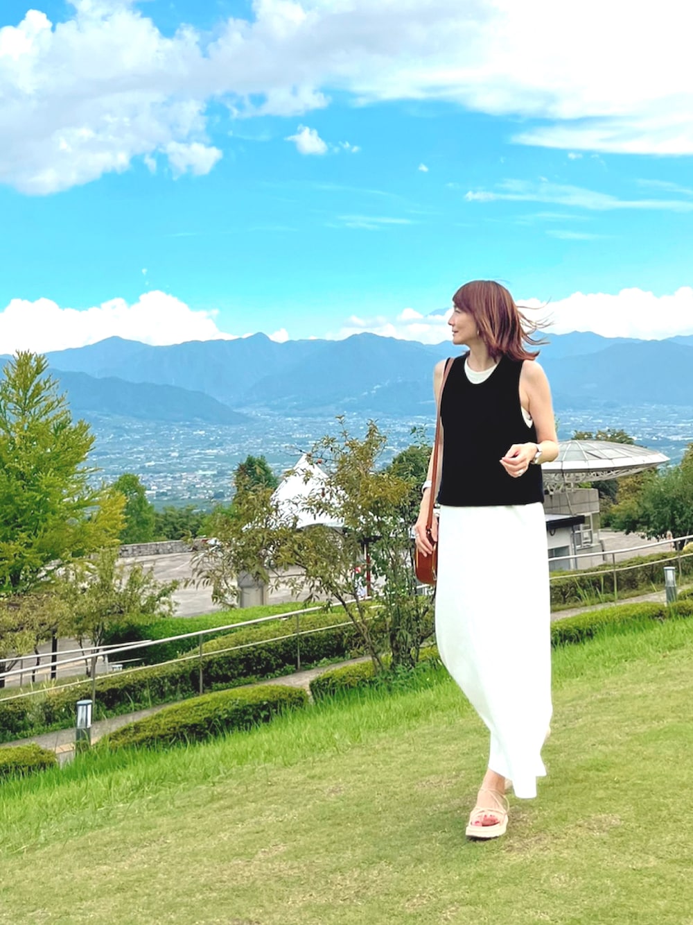 ホワイト系のワンピース、ブラウン系のショルダーバッグ、ホワイト系のサンダルを着用したレディースの夏コーディネートの2枚目の写真