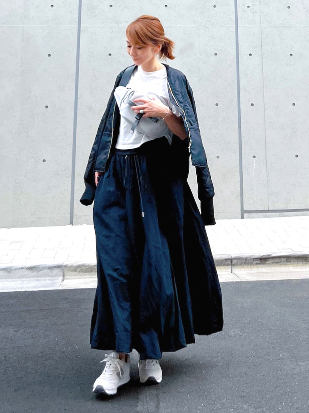 ホワイト系のスニーカー、ブルー系のスカート、ブラック系のブルゾンを着用したレディースの秋コーディネートの2枚目の写真