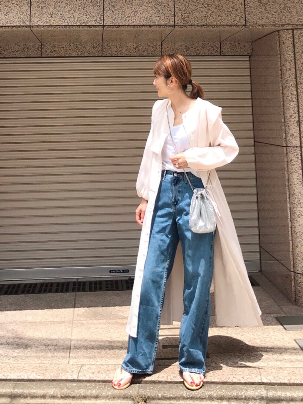 ブルー系のデニムパンツ、ホワイト系のシャツワンピース、ゴールド系のサンダルを着用したレディースの夏コーディネートの3枚目の写真