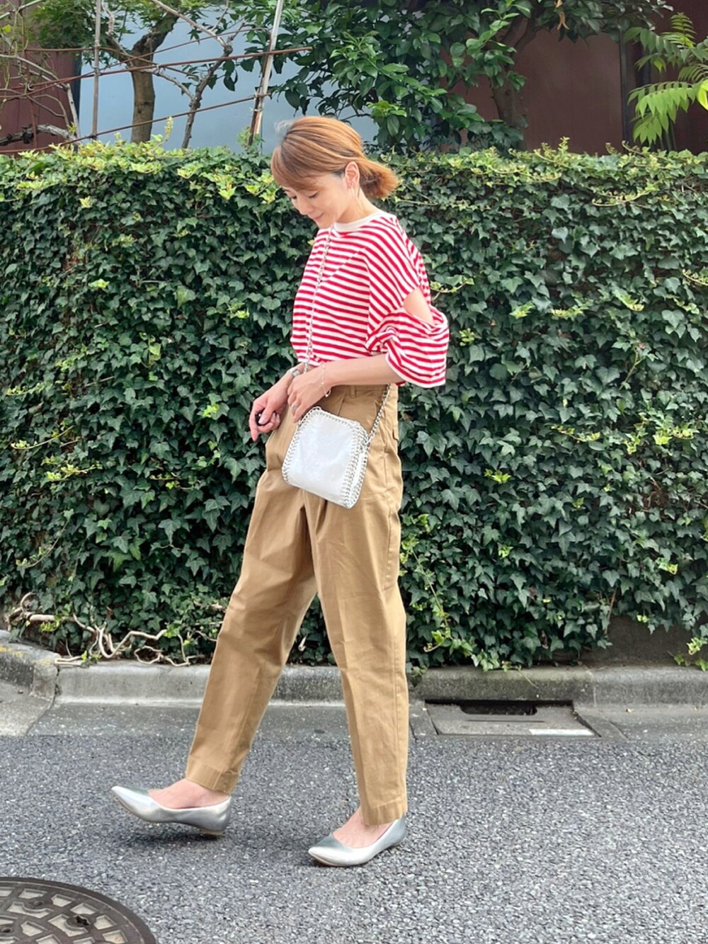 レッド系のTシャツ/カットソー、イエロー系のチノパンツ、ホワイト系のショルダーバッグを着用したレディースの夏コーディネートの2枚目の写真