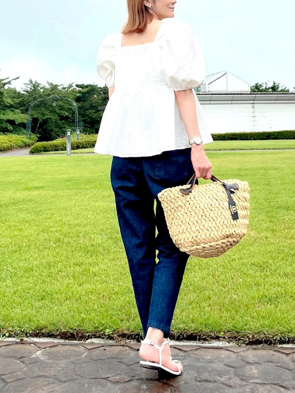 ホワイト系のシャツ/ブラウス、ブルー系のデニムパンツ、ベージュ系のハンドバッグを着用したレディースの夏コーディネートの2枚目の写真