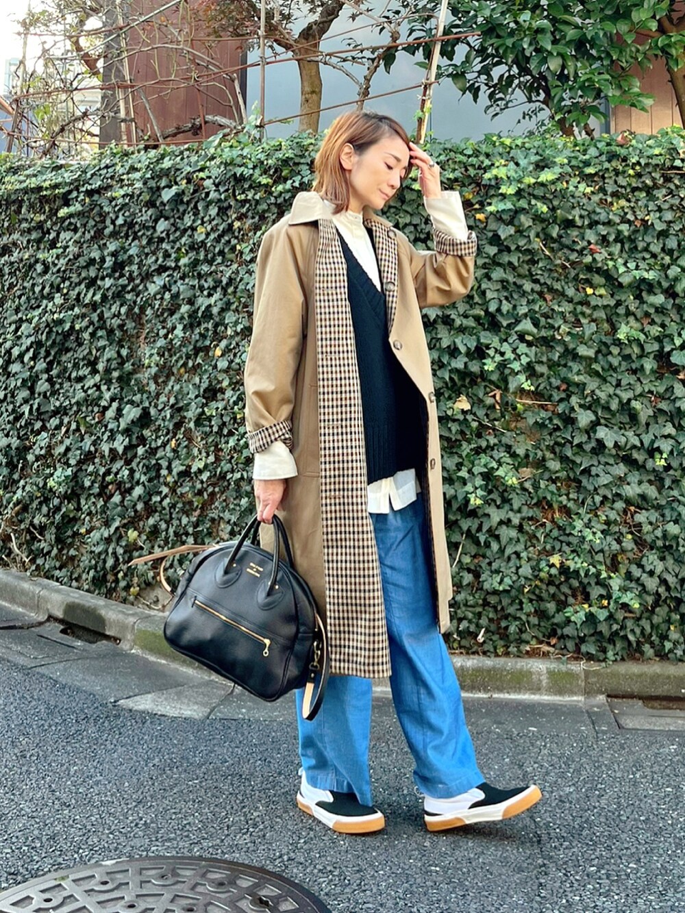 ベージュ系のステンカラーコート、ブルー系のその他パンツ、ブラック系のショルダーバッグを着用したレディースの冬コーディネートの2枚目の写真