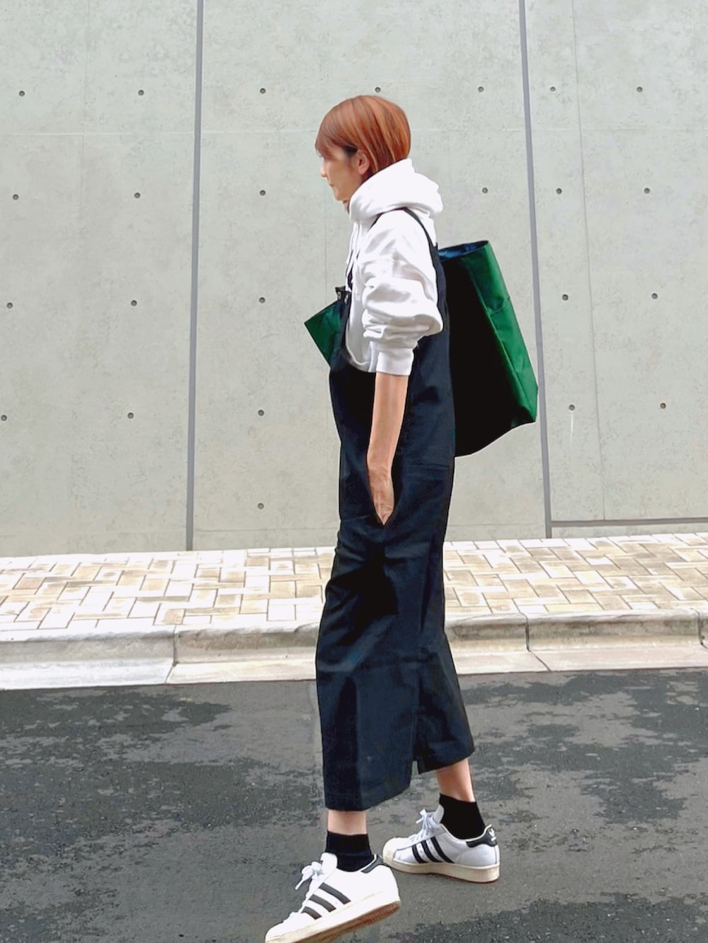グリーン系のトートバッグ、ホワイト系のパーカー、ブラック系のスカートを着用したレディースの秋コーディネートの3枚目の写真