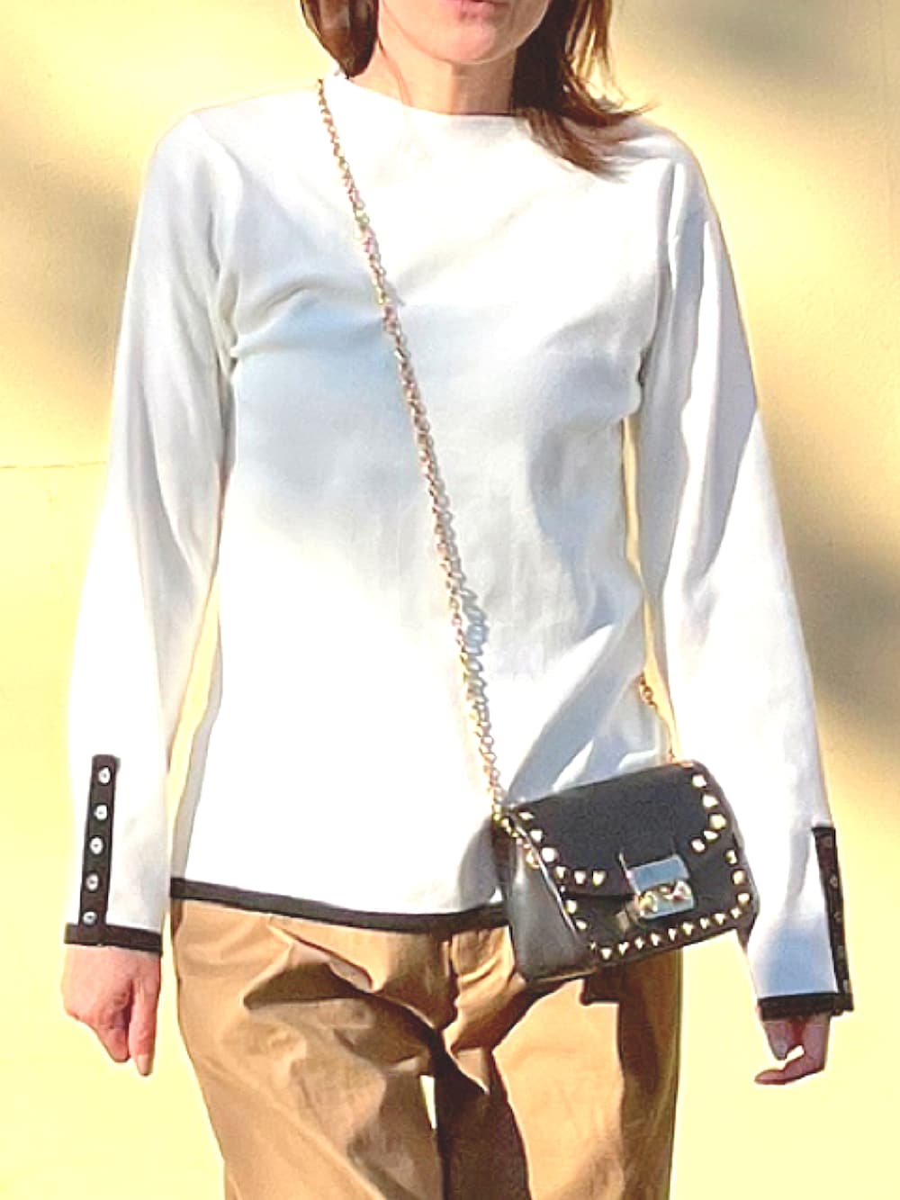 ホワイト系のニット/セーター、イエロー系のチノパンツ、ブラック系のパンプスを着用したレディースの冬コーディネートの2枚目の写真