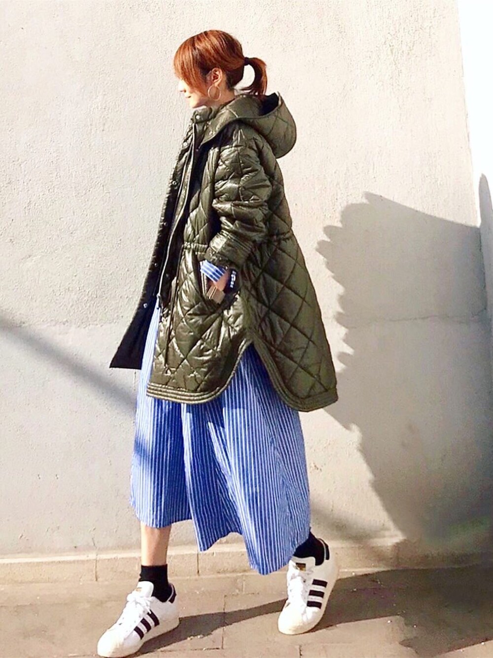 グリーン系のブルゾン、ブラック系のトートバッグ、ブルー系のワンピースを着用したレディースの秋コーディネートの2枚目の写真