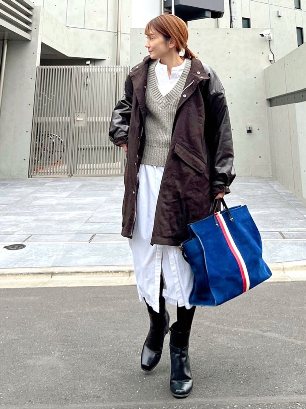 ブラウン系のミリタリージャケット、ブルー系のトートバッグ、ホワイト系のシャツワンピースを着用したレディースの冬コーディネートの3枚目の写真