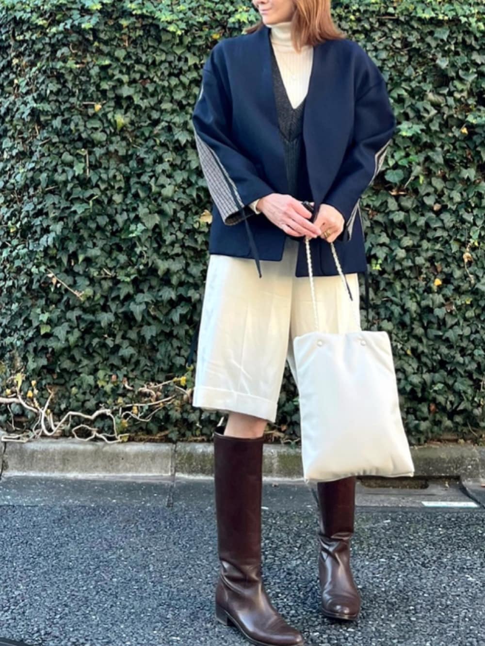 ブラウン系のブーツ、ブルー系のノーカラージャケット、ホワイト系のトートバッグを着用したレディースの冬コーディネートの2枚目の写真