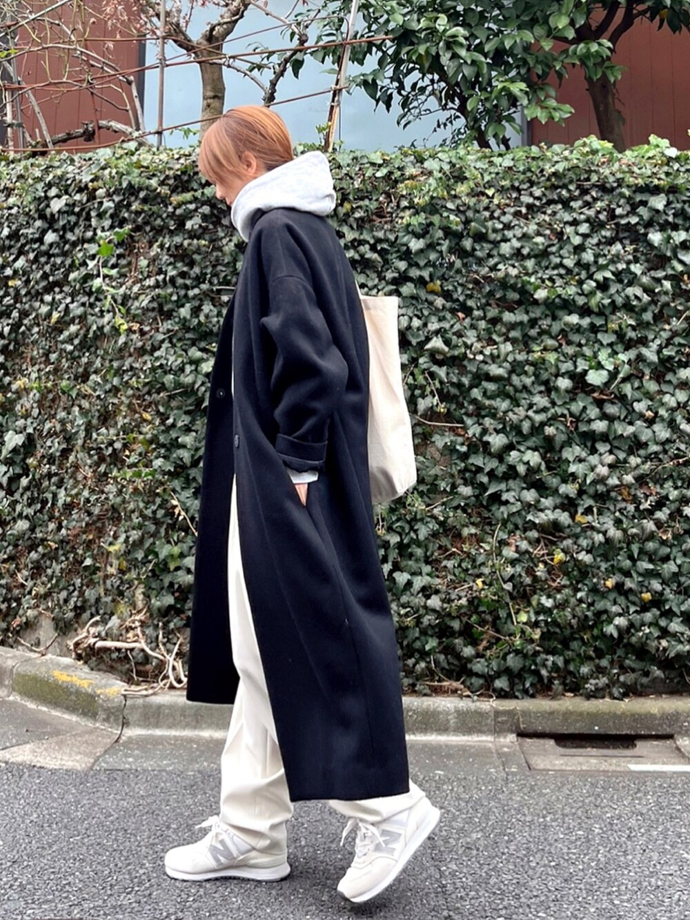 ホワイト系のスラックス、ブラック系のノーカラーコート、グレー系のTシャツ/カットソーを着用したレディースの冬コーディネートの2枚目の写真