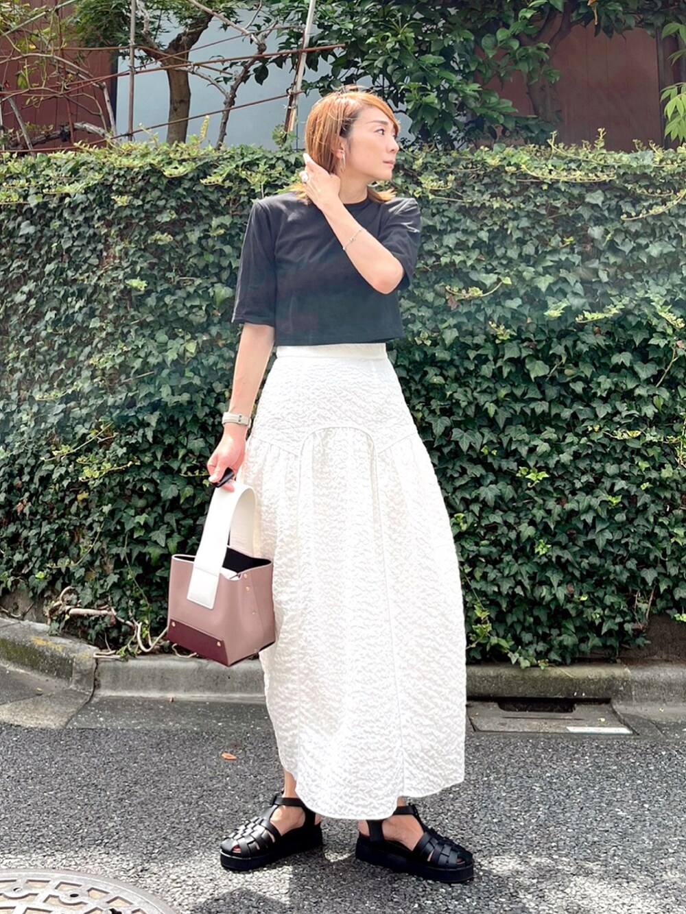 ブラック系のTシャツ/カットソー、ホワイト系のスカート、パープル系のバッグを着用したレディースの秋コーディネートの3枚目の写真