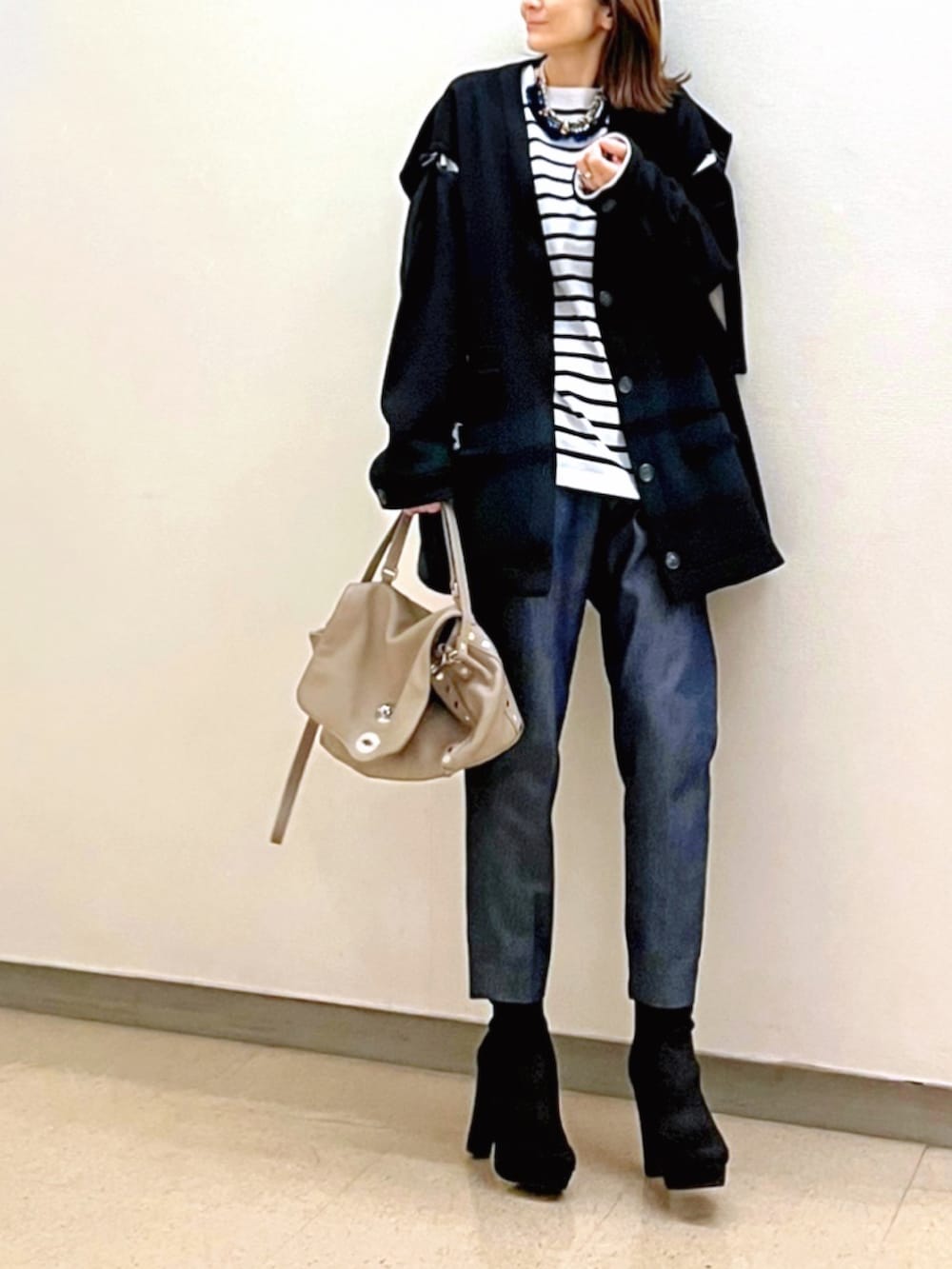 ブラック系のノーカラージャケット、ホワイト系のTシャツ/カットソー、グレー系のハンドバッグを着用したレディースの春コーディネートの2枚目の写真