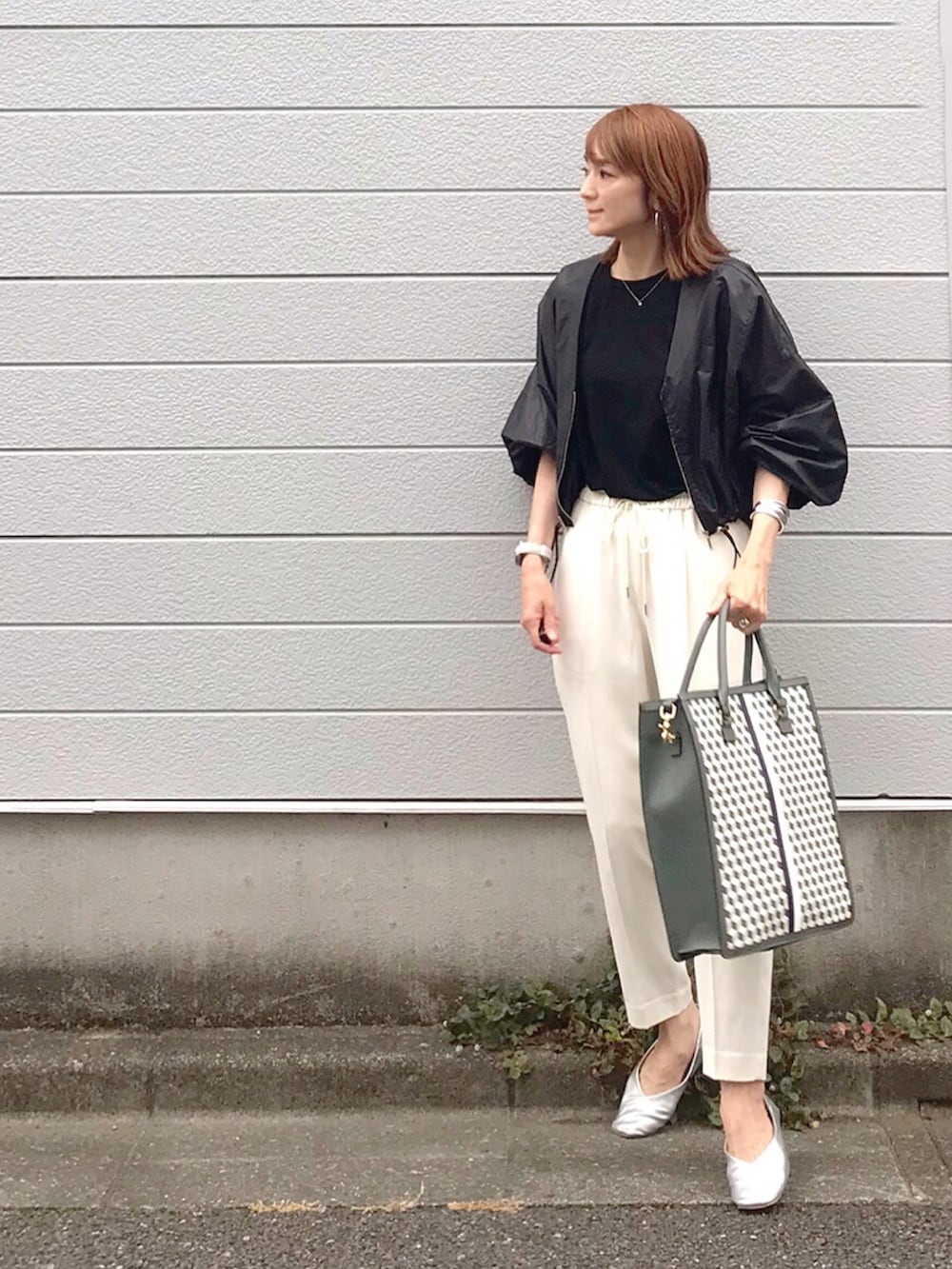 ブラック系のトートバッグ、ブラック系のブルゾン、ホワイト系のその他パンツを着用したレディースの夏コーディネートの2枚目の写真
