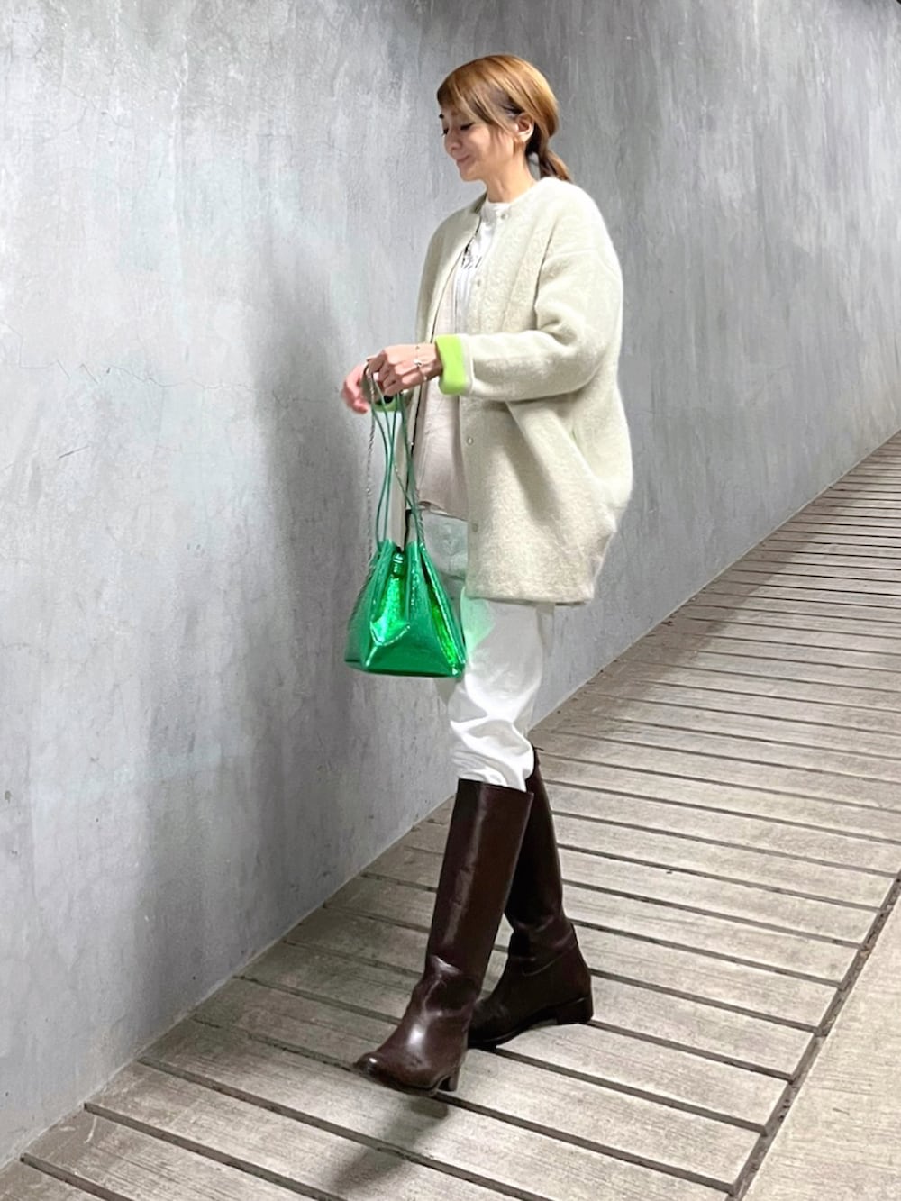 ホワイト系のカーディガン/ボレロ、グリーン系のショルダーバッグ、ブラウン系のブーツを着用したレディースの冬コーディネートの3枚目の写真