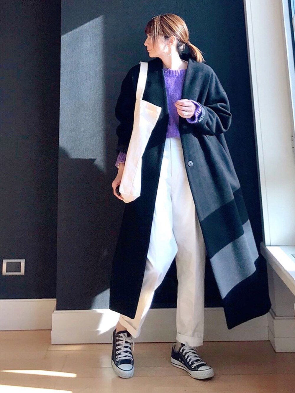 ブラック系のノーカラーコート、パープル系のニット/セーター、ホワイト系のその他パンツを着用したレディースの冬コーディネートの2枚目の写真