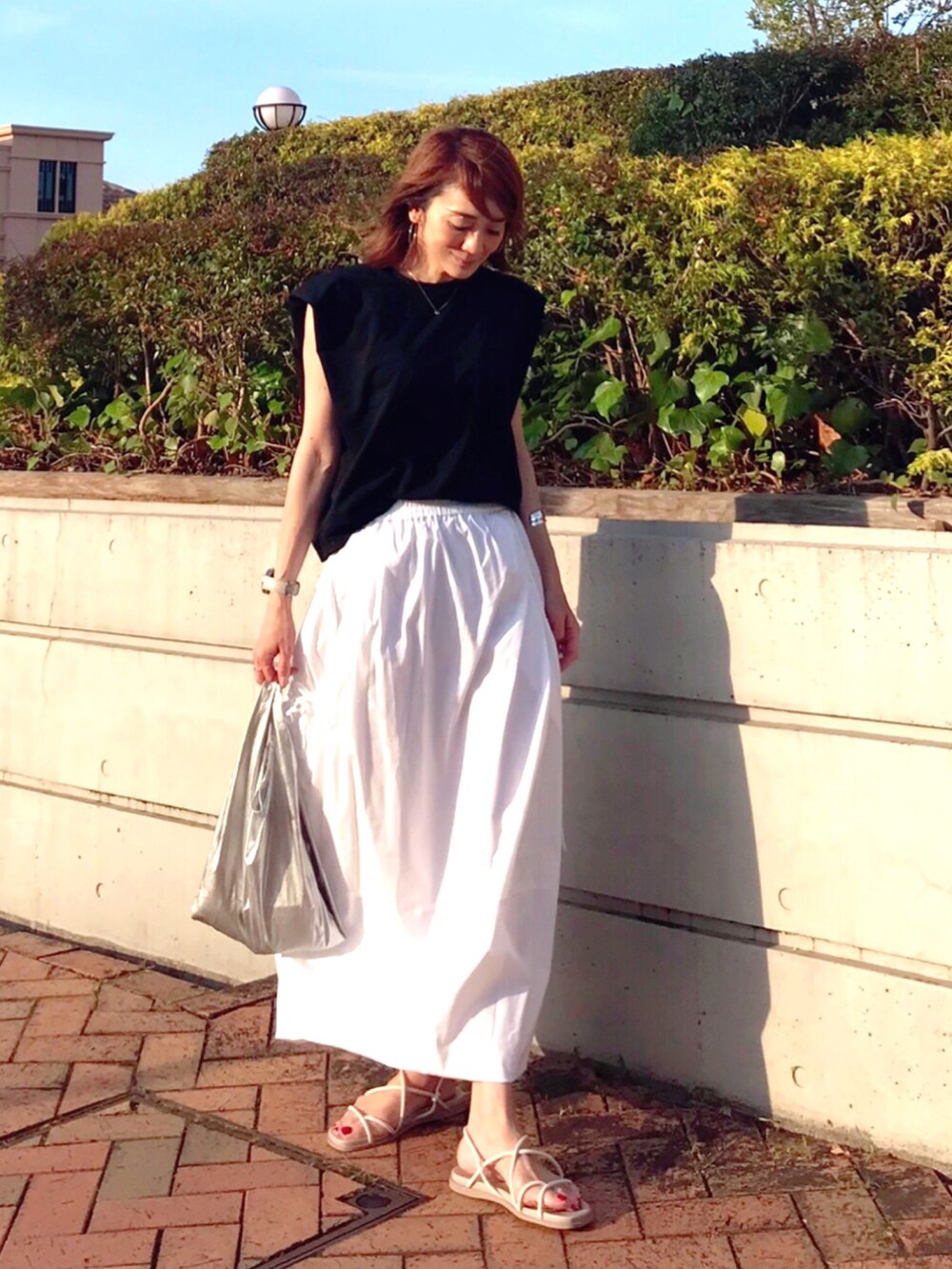 ホワイト系のスカート、シルバー系のエコバッグ/サブバッグ、ブラック系のTシャツ/カットソーを着用したレディースの夏コーディネートの2枚目の写真