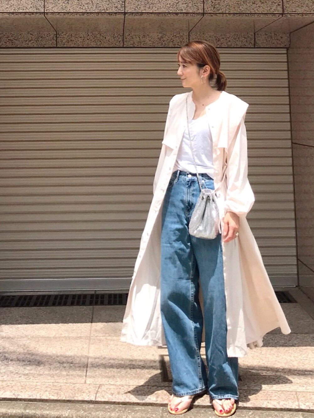 ブルー系のデニムパンツ、ホワイト系のシャツワンピース、ゴールド系のサンダルを着用したレディースの夏コーディネートの4枚目の写真