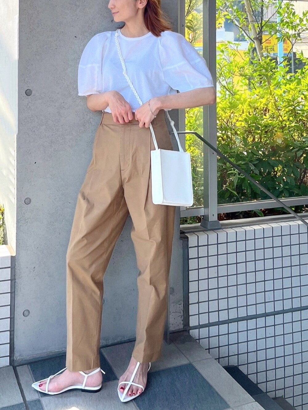 ホワイト系のショルダーバッグ、イエロー系のチノパンツ、ホワイト系のサンダルを着用したレディースの夏コーディネートの2枚目の写真