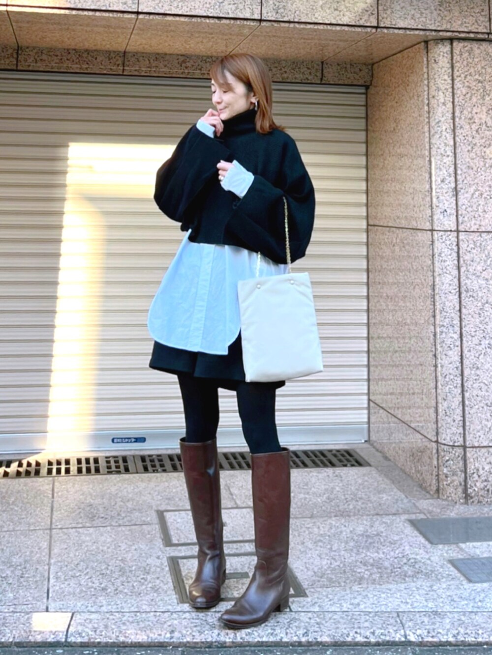 ブラウン系のブーツ、ブラック系のニット/セーター、ホワイト系のシャツ/ブラウスを着用したレディースの冬コーディネートの2枚目の写真