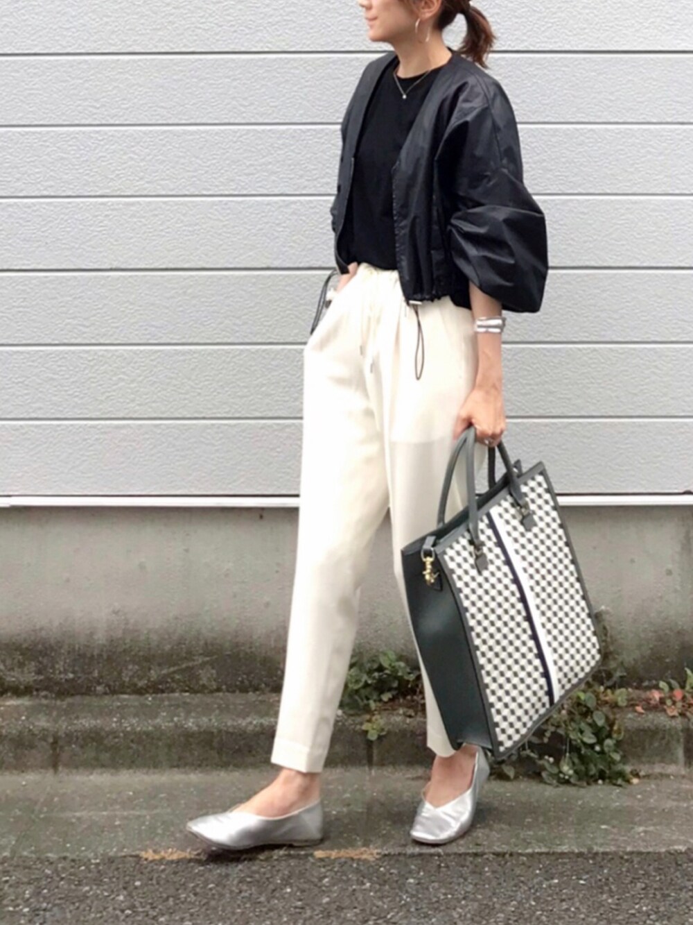 ブラック系のトートバッグ、ブラック系のブルゾン、ホワイト系のその他パンツを着用したレディースの夏コーディネートの3枚目の写真