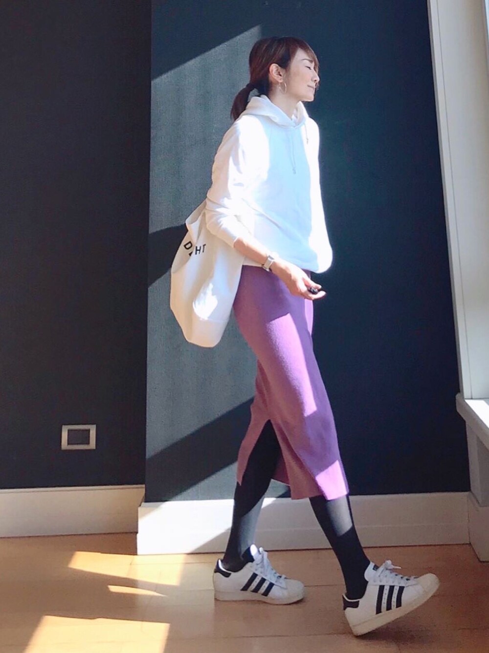 ピンク系のスカート、ホワイト系のパーカー、ホワイト系のトートバッグを着用したレディースの冬コーディネートの2枚目の写真