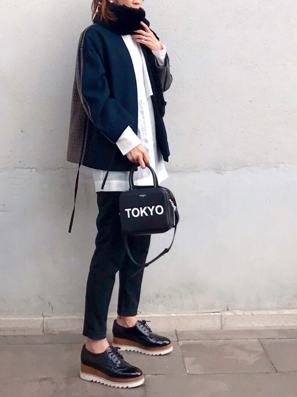 ブラック系のハンドバッグ、ブルー系のノーカラージャケット、ブラック系のドレスシューズを着用したレディースの秋コーディネートの2枚目の写真