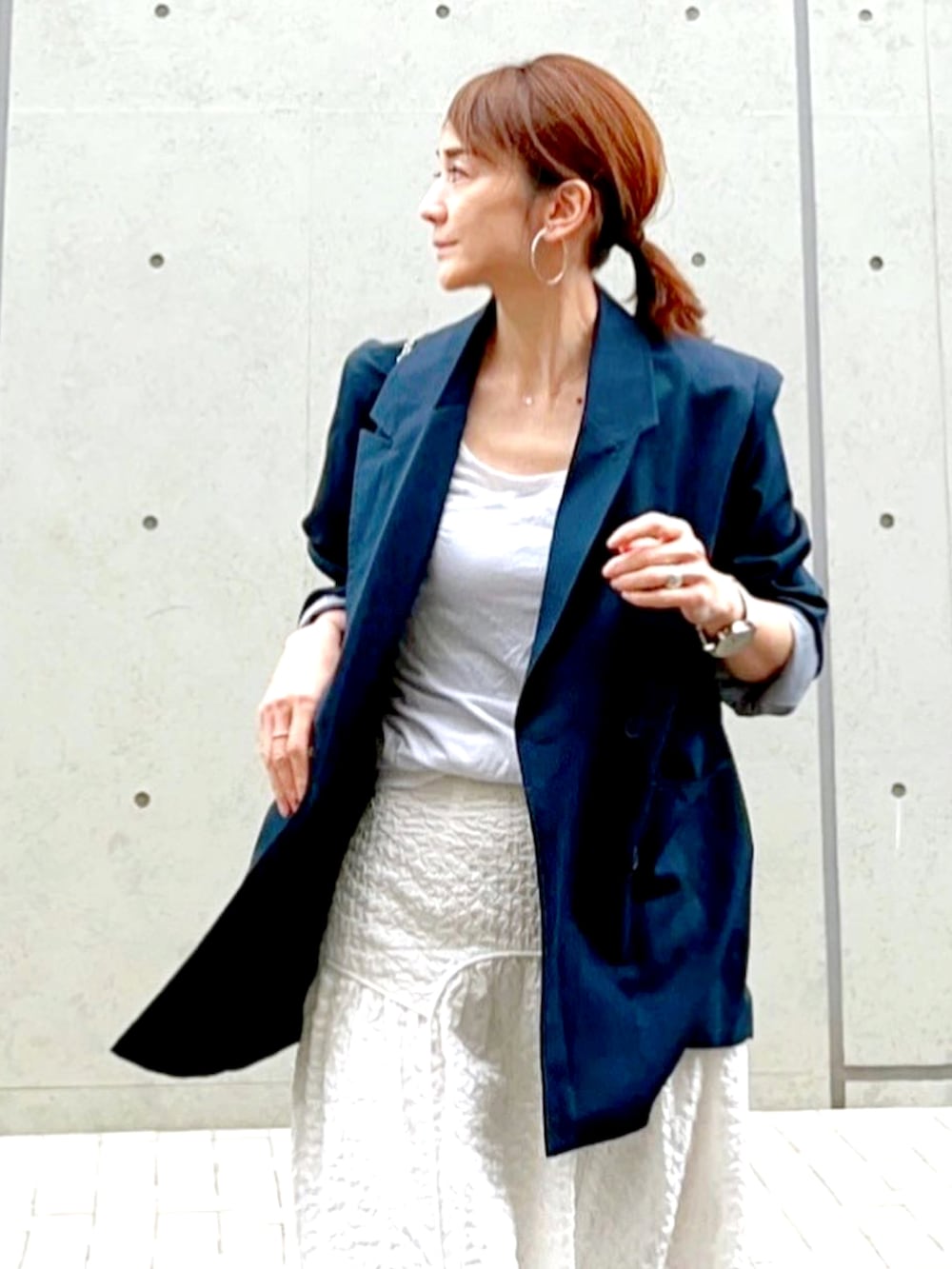 ブルー系のテーラードジャケット、ホワイト系のスカート、シルバー系のシューズを着用したレディースの春コーディネートの3枚目の写真