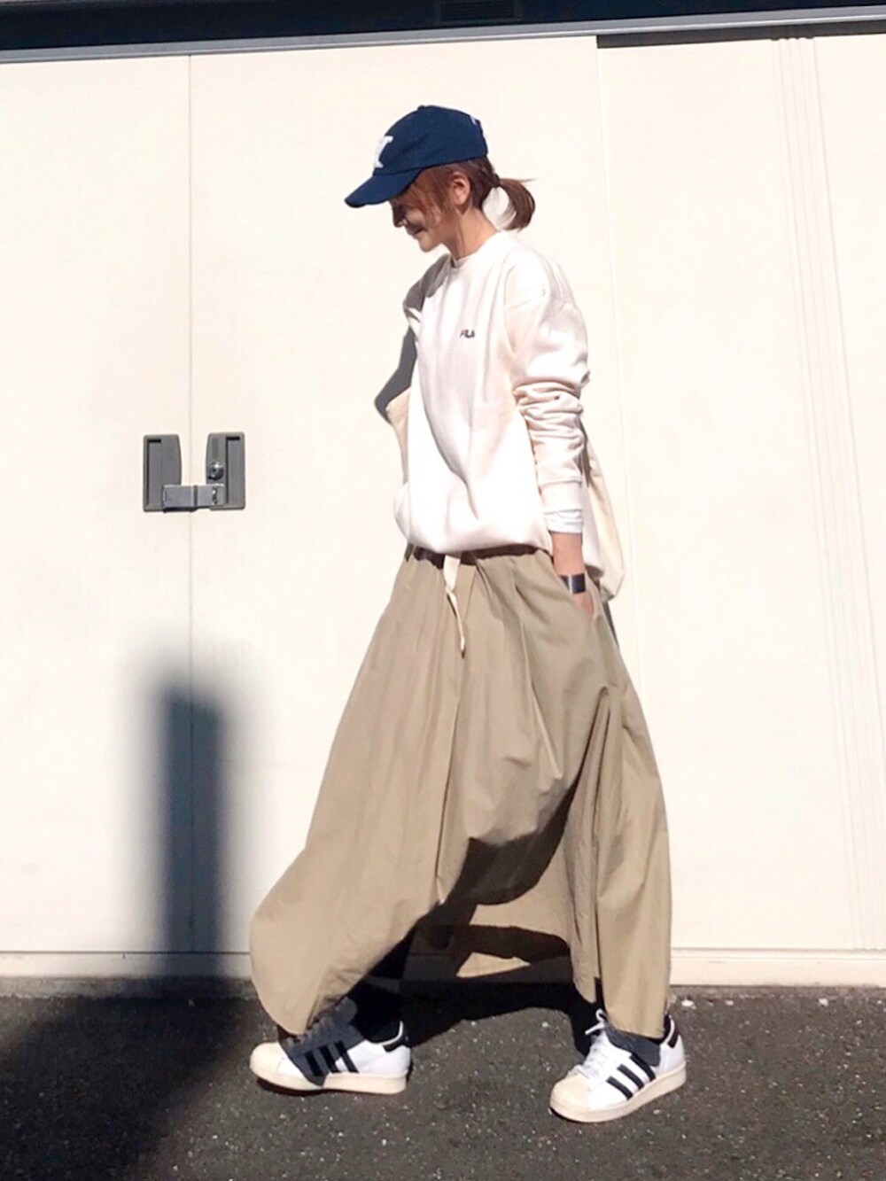 ホワイト系のスウェット、ベージュ系のスカート、ホワイト系のスニーカーを着用したレディースの冬コーディネートの2枚目の写真