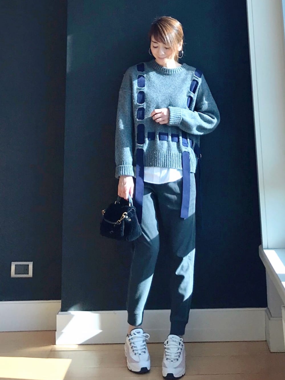 ホワイト系のスニーカー、グレー系のニット/セーター、ブルー系のショルダーバッグを着用したレディースの冬コーディネートの2枚目の写真