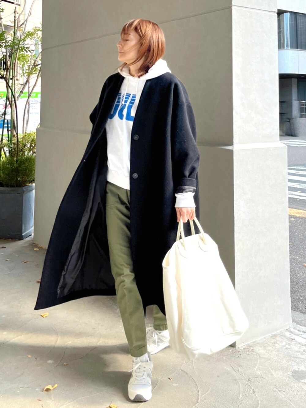 ホワイト系のスウェット、ホワイト系のトートバッグ、ブラック系のノーカラーコートを着用したレディースの冬コーディネートの3枚目の写真