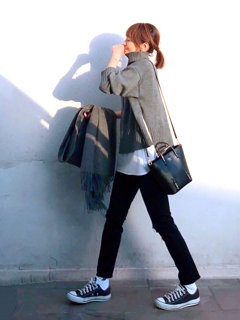 グレー系のニット/セーター、ブラック系のトートバッグ、ブラック系のスニーカーを着用したレディースの秋コーディネートの2枚目の写真