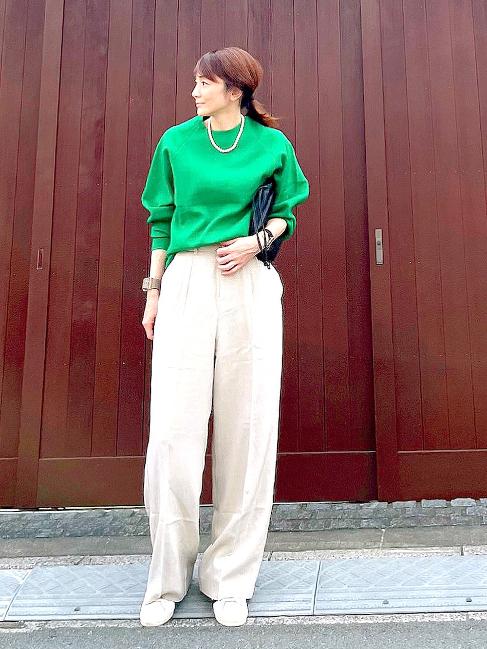 グリーン系のニット/セーター、ベージュ系のその他パンツ、ブラウン系のハンドバッグを着用したレディースの秋コーディネートの3枚目の写真