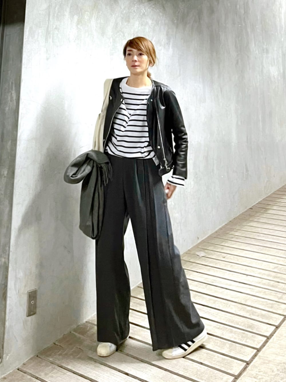 グレー系のスラックス、ホワイト系のTシャツ/カットソー、ホワイト系のスニーカーを着用したレディースの春コーディネートの2枚目の写真