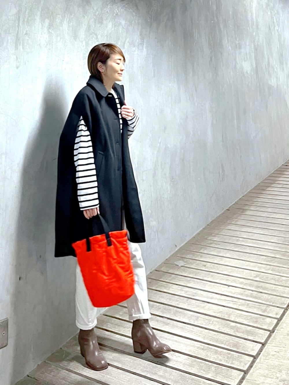 ホワイト系のTシャツ/カットソー、オレンジ系のトートバッグ、ベージュ系のブーツを着用したレディースの春コーディネートの2枚目の写真