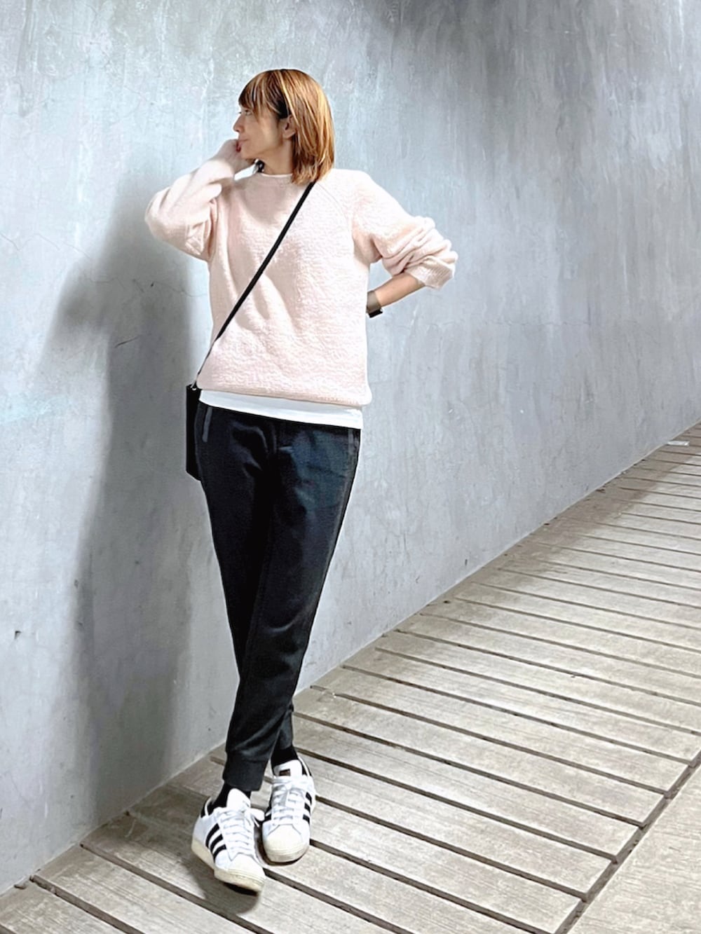 ピンク系のニット/セーター、ブラック系のトートバッグ、ホワイト系のスニーカーを着用したレディースの冬コーディネートの2枚目の写真