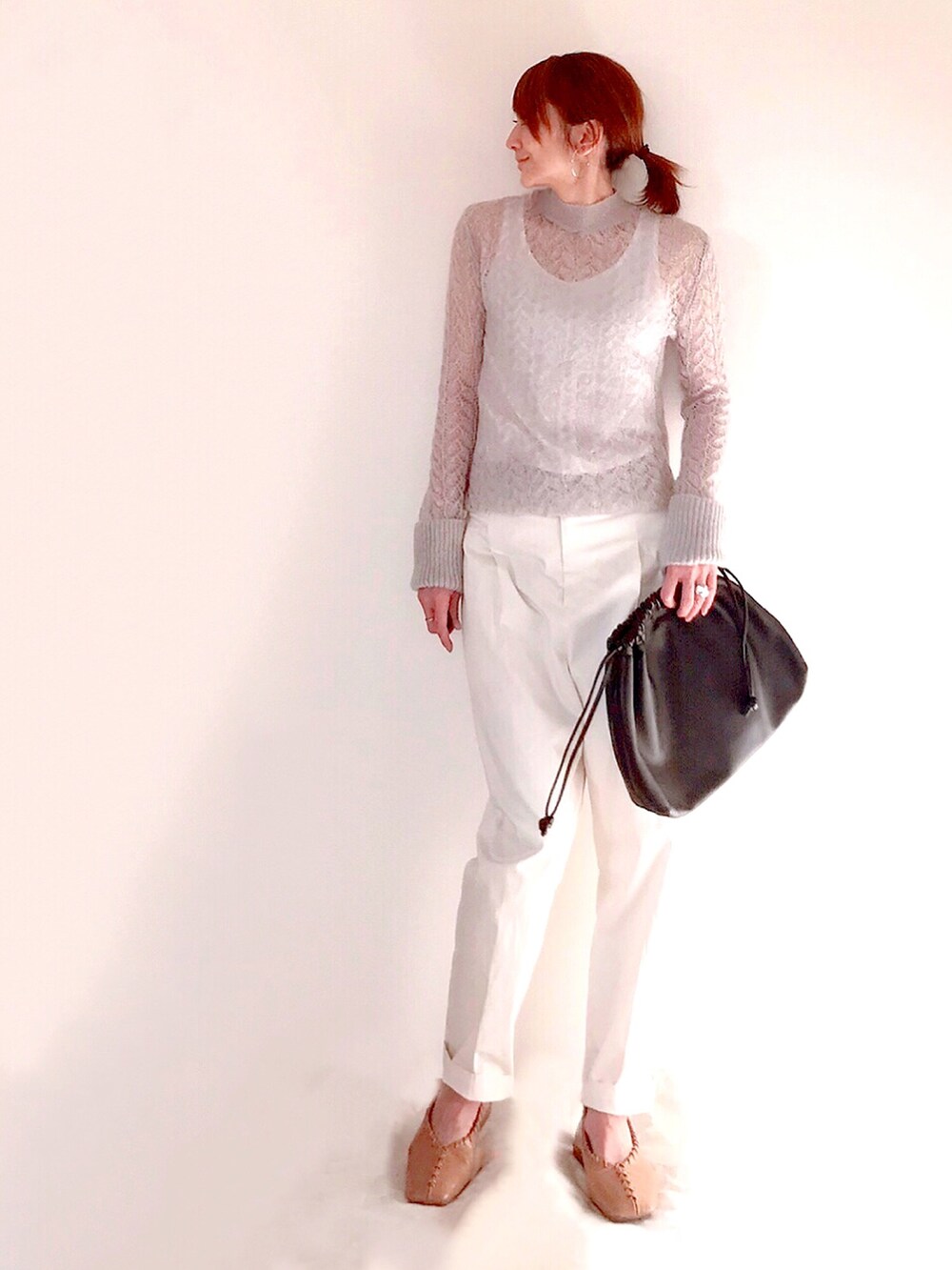 グレー系のニット/セーター、ブラウン系のハンドバッグ、ホワイト系のその他パンツを着用したレディースの冬コーディネートの2枚目の写真