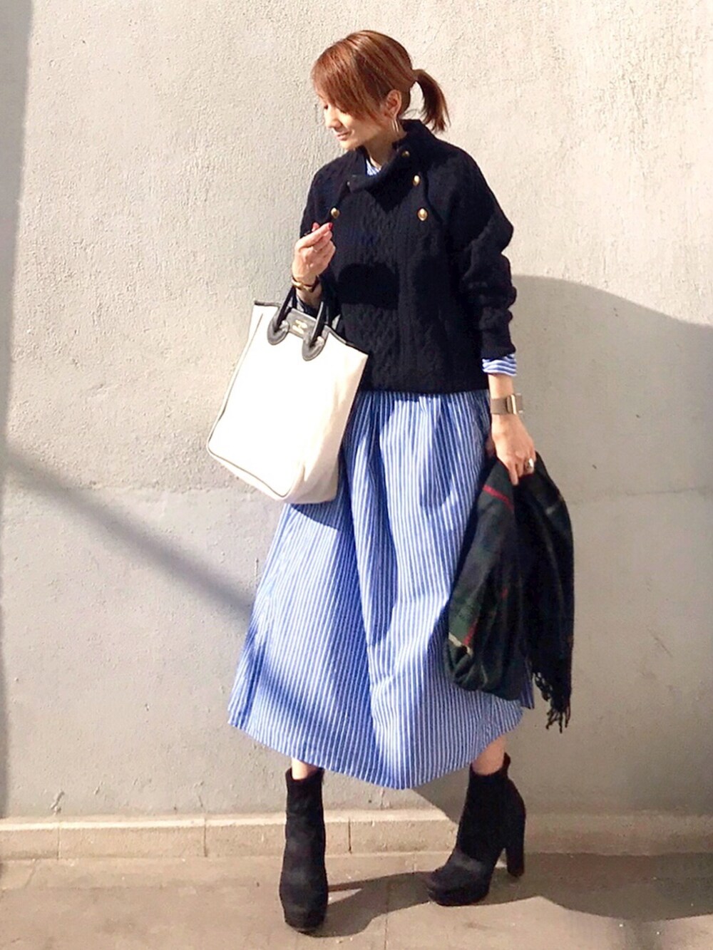 その他のトートバッグ、ブラック系のブーツ、ブルー系のニット/セーターを着用したレディースの秋コーディネートの2枚目の写真