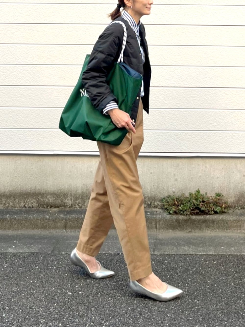 グリーン系のトートバッグ、イエロー系のチノパンツ、シルバー系のシューズを着用したレディースの秋コーディネートの2枚目の写真