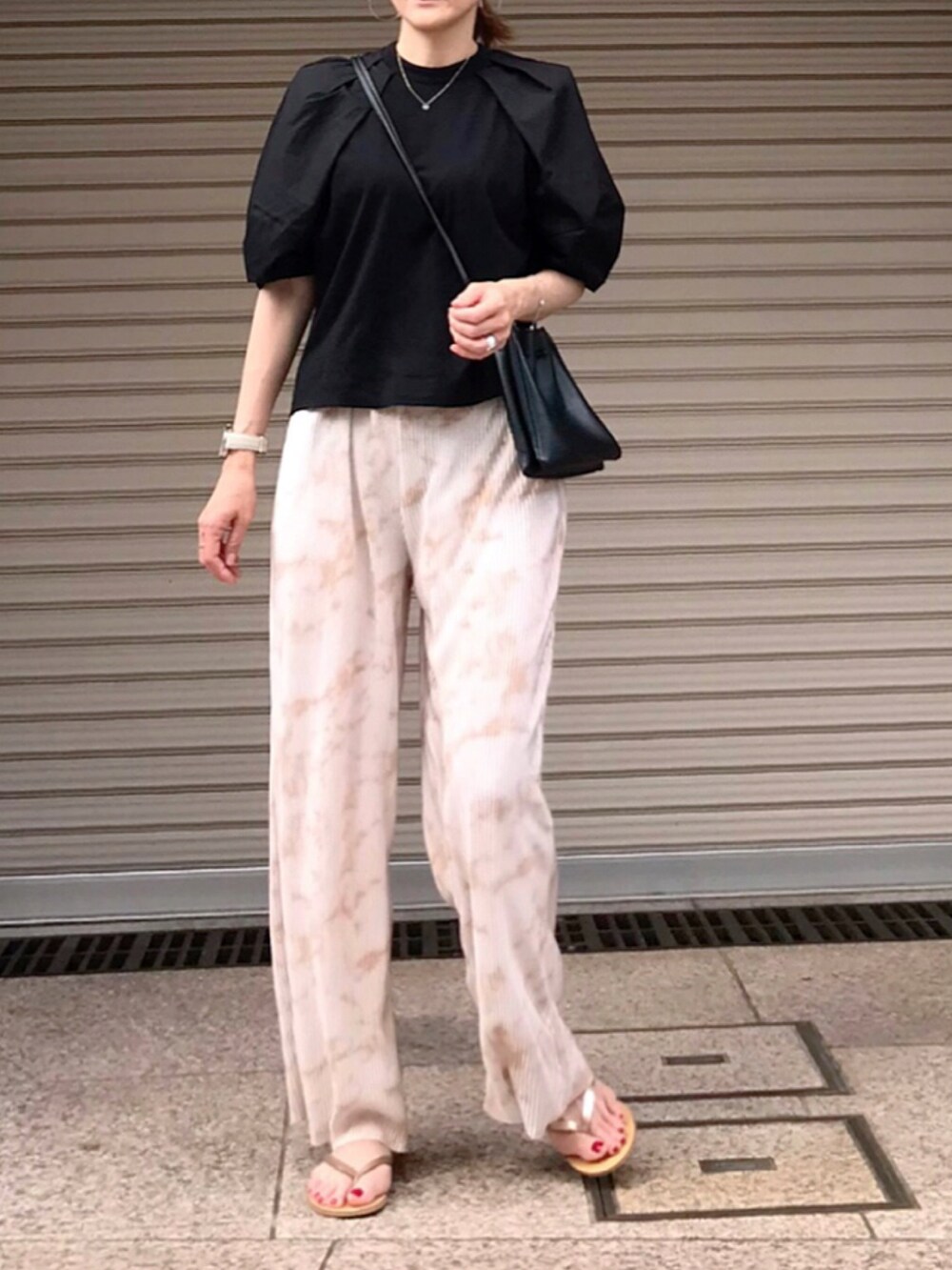 ブラック系のショルダーバッグ、ブラック系のTシャツ/カットソー、ベージュ系のパンツを着用したレディースの夏コーディネートの2枚目の写真