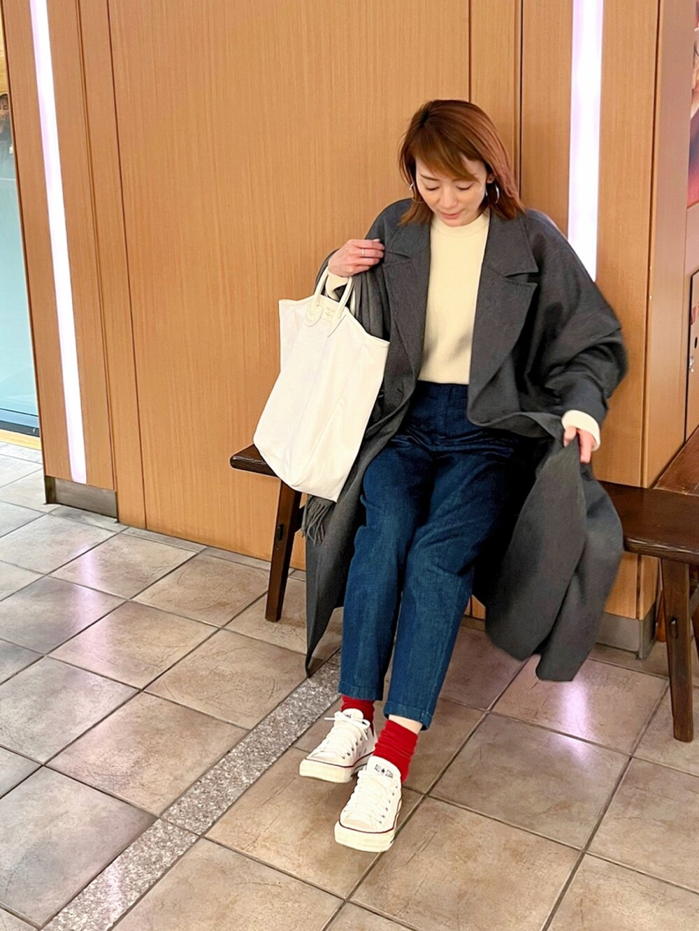 ブルー系のデニムパンツ、ホワイト系のニット/セーター、ホワイト系のトートバッグを着用したレディースの冬コーディネートの2枚目の写真