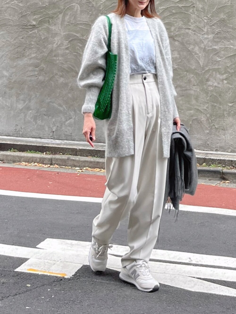 ホワイト系のスラックス、ホワイト系のTシャツ/カットソー、グリーン系のトートバッグを着用したレディースの秋コーディネートの2枚目の写真