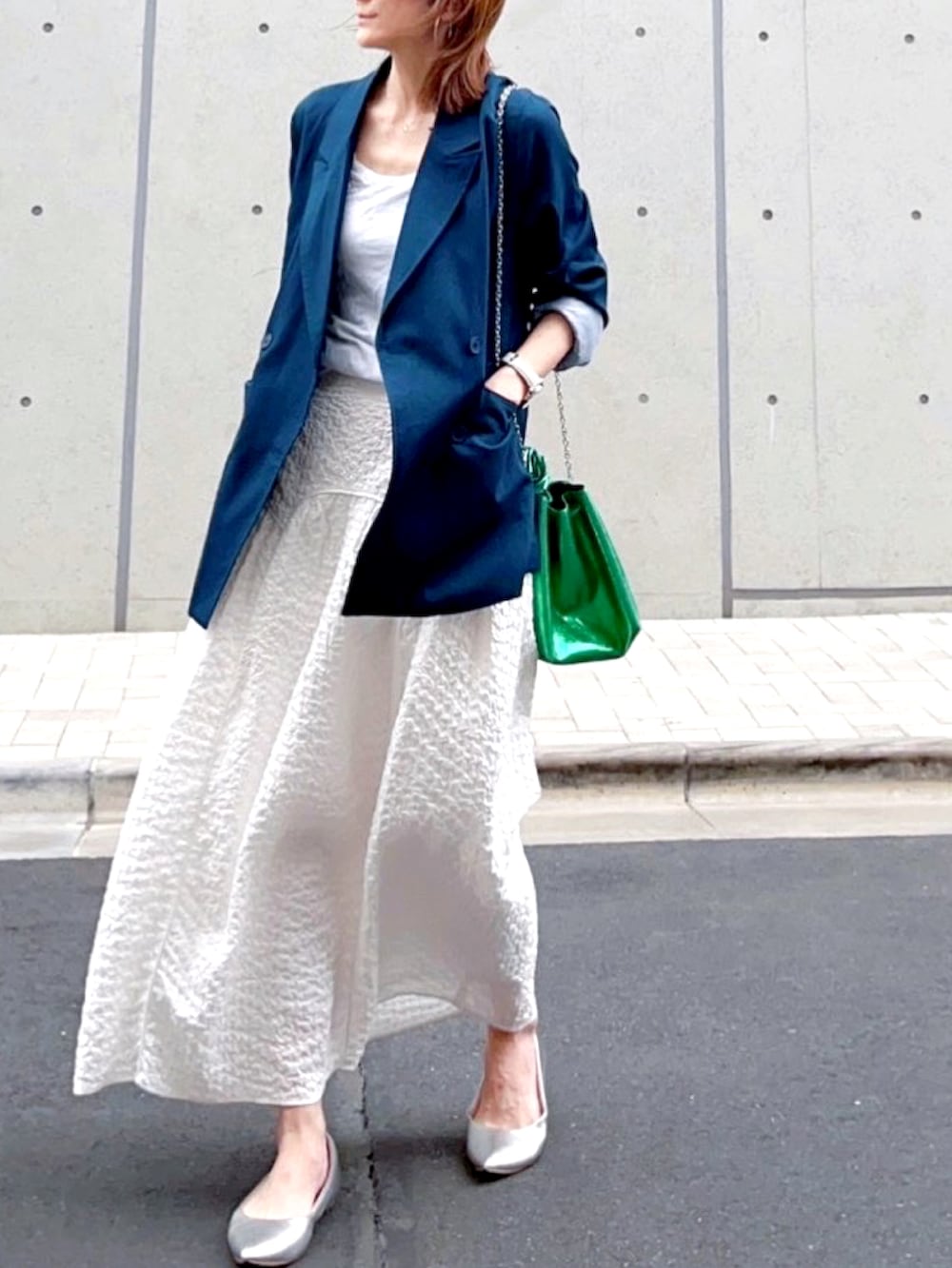 ブルー系のテーラードジャケット、ホワイト系のスカート、シルバー系のシューズを着用したレディースの春コーディネートの2枚目の写真