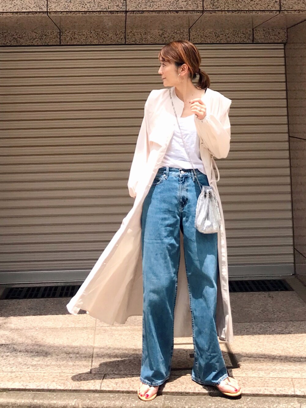 ブルー系のデニムパンツ、ホワイト系のシャツワンピース、ゴールド系のサンダルを着用したレディースの夏コーディネートの2枚目の写真