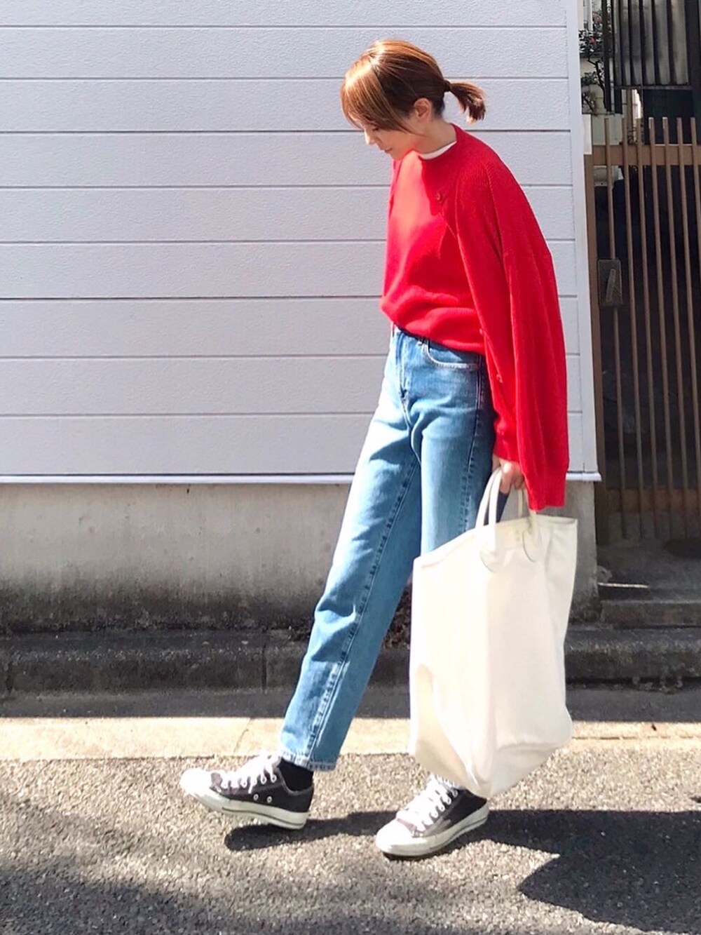 レッド系のニット/セーター、レッド系のカーディガン/ボレロ、ブルー系のデニムパンツを着用したレディースの春コーディネートの2枚目の写真