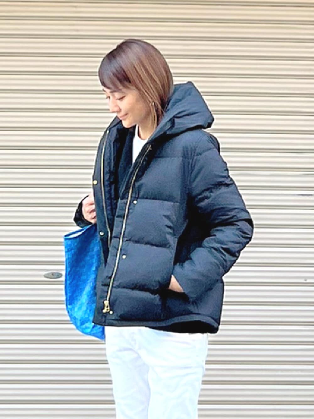 ブルー系のトートバッグ、ブラック系のダウンジャケット/コート、ブラウン系のブーツを着用したレディースの冬コーディネートの2枚目の写真