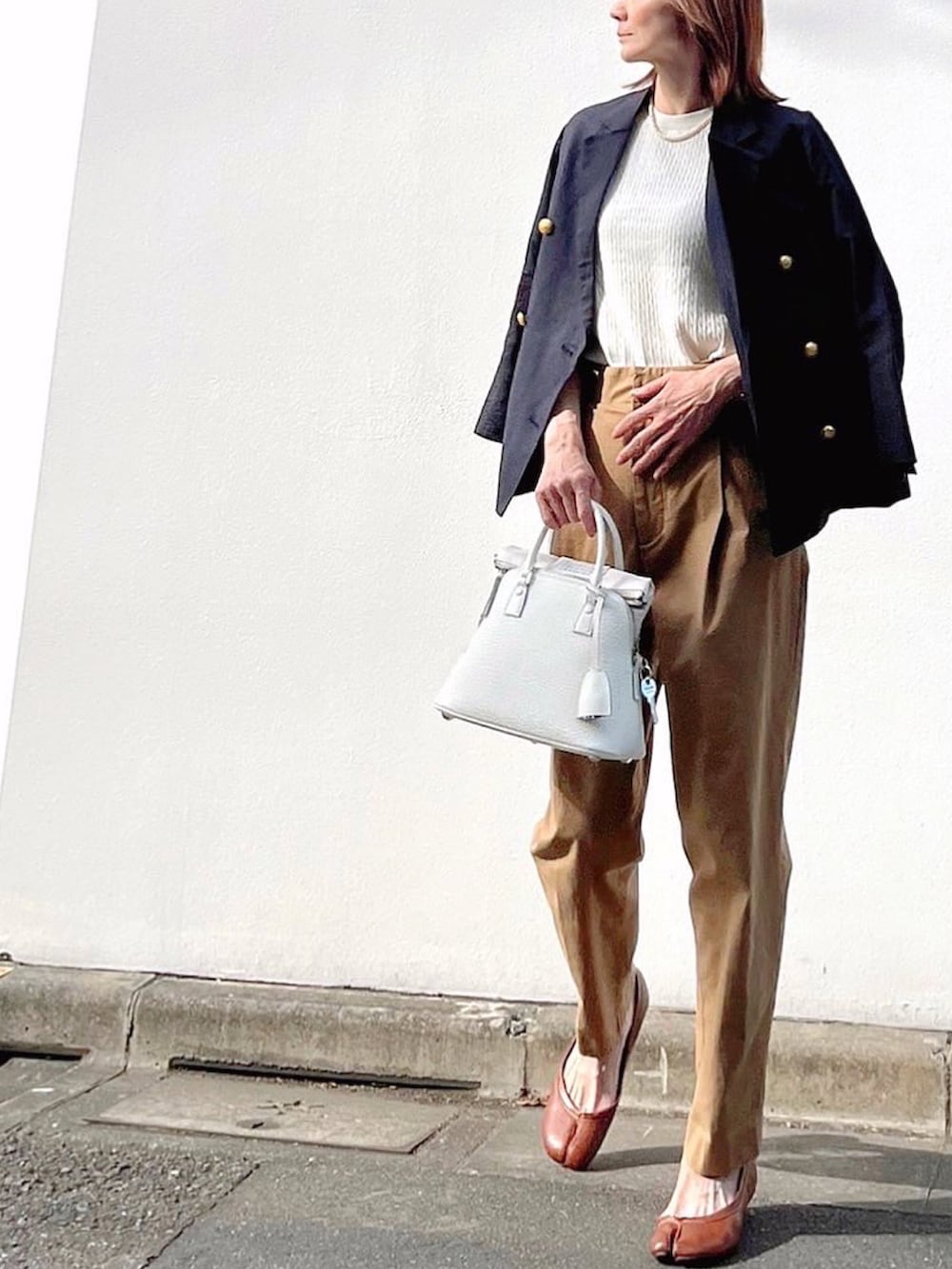 イエロー系のチノパンツ、ホワイト系のハンドバッグ、ブルー系のテーラードジャケットを着用したレディースの春コーディネートの2枚目の写真