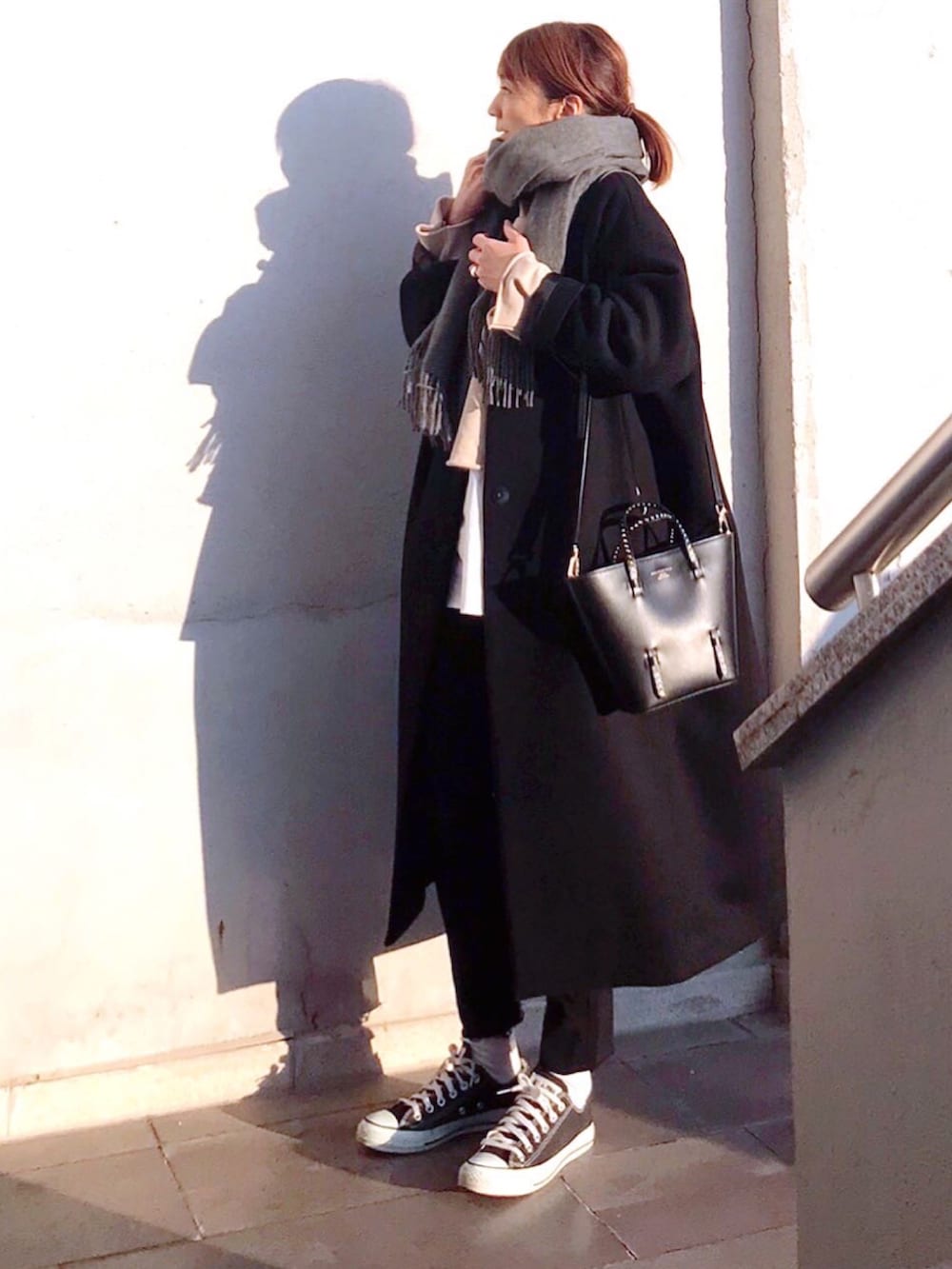 ブラック系のノーカラーコート、ホワイト系のスウェット、ブラック系のトートバッグを着用したレディースの冬コーディネートの2枚目の写真